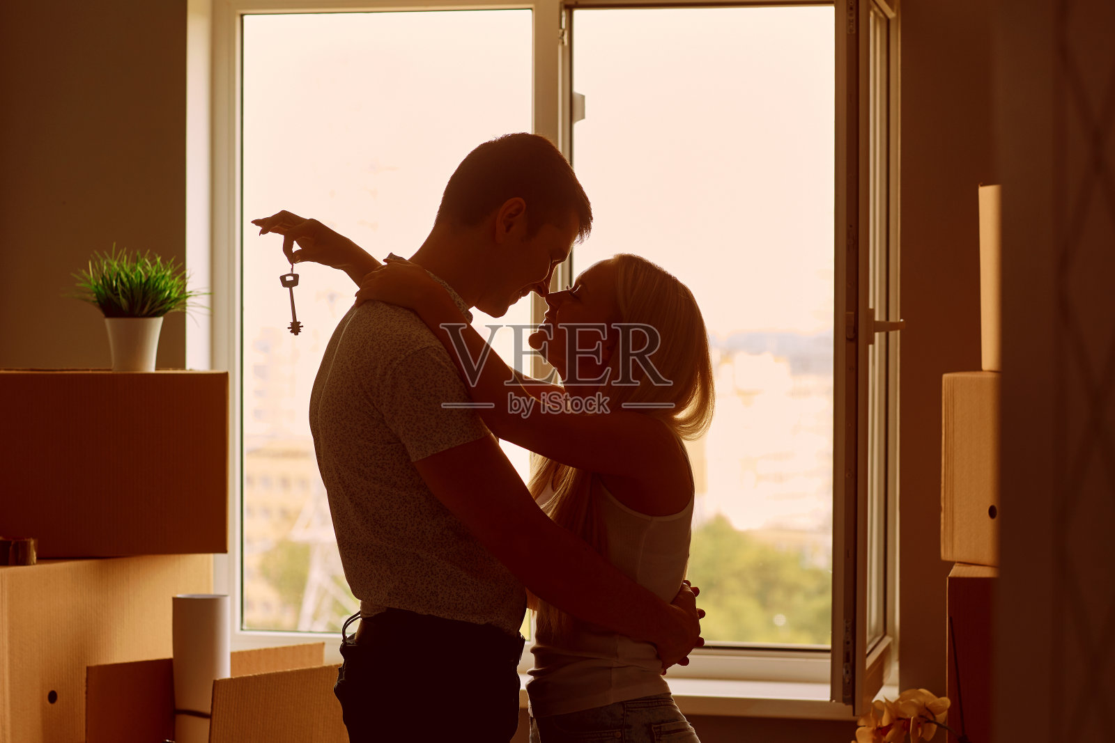 一对年轻夫妇在新公寓里拿着钥匙。照片摄影图片