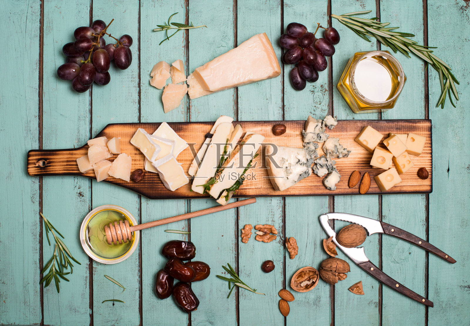 奶酪选择在木制的乡村板。奶酪拼盘与不同的奶酪，葡萄，坚果，蜂蜜和枣在破旧别致的背景。照片摄影图片