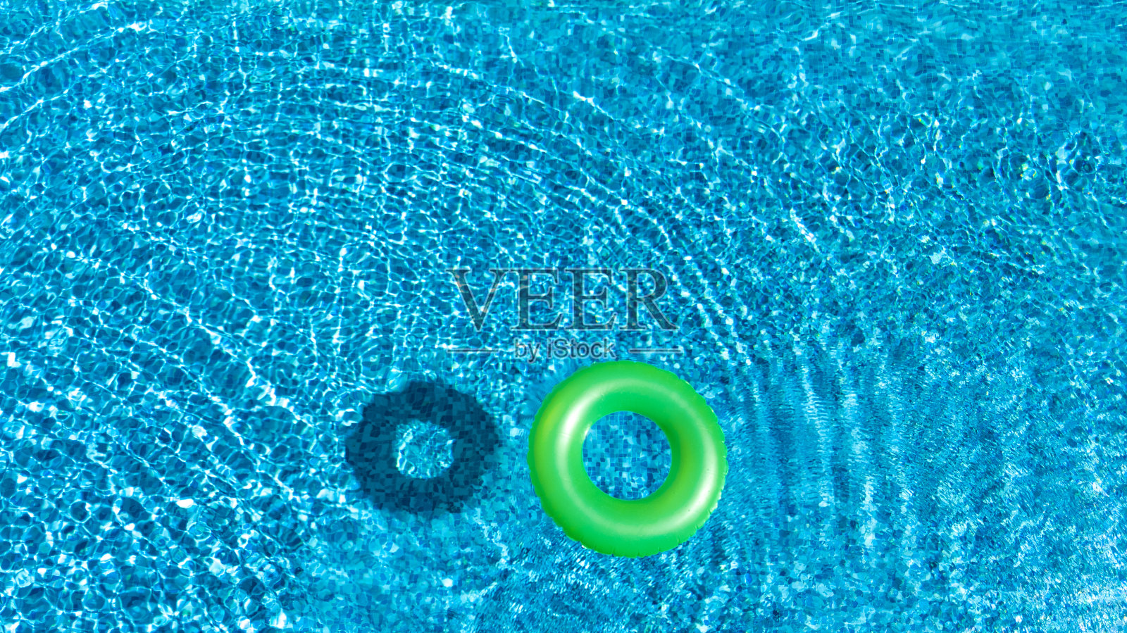 鸟瞰图的彩色充气圈甜甜圈玩具在游泳池的水从上面，家庭度假的概念背景照片摄影图片