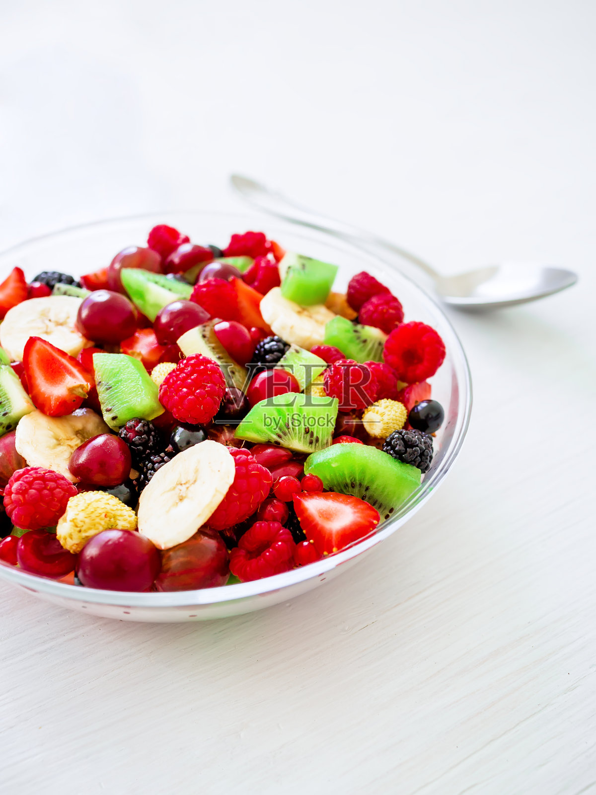 新鲜的沙拉，水果和浆果，玻璃碗，白色的桌子。照片摄影图片