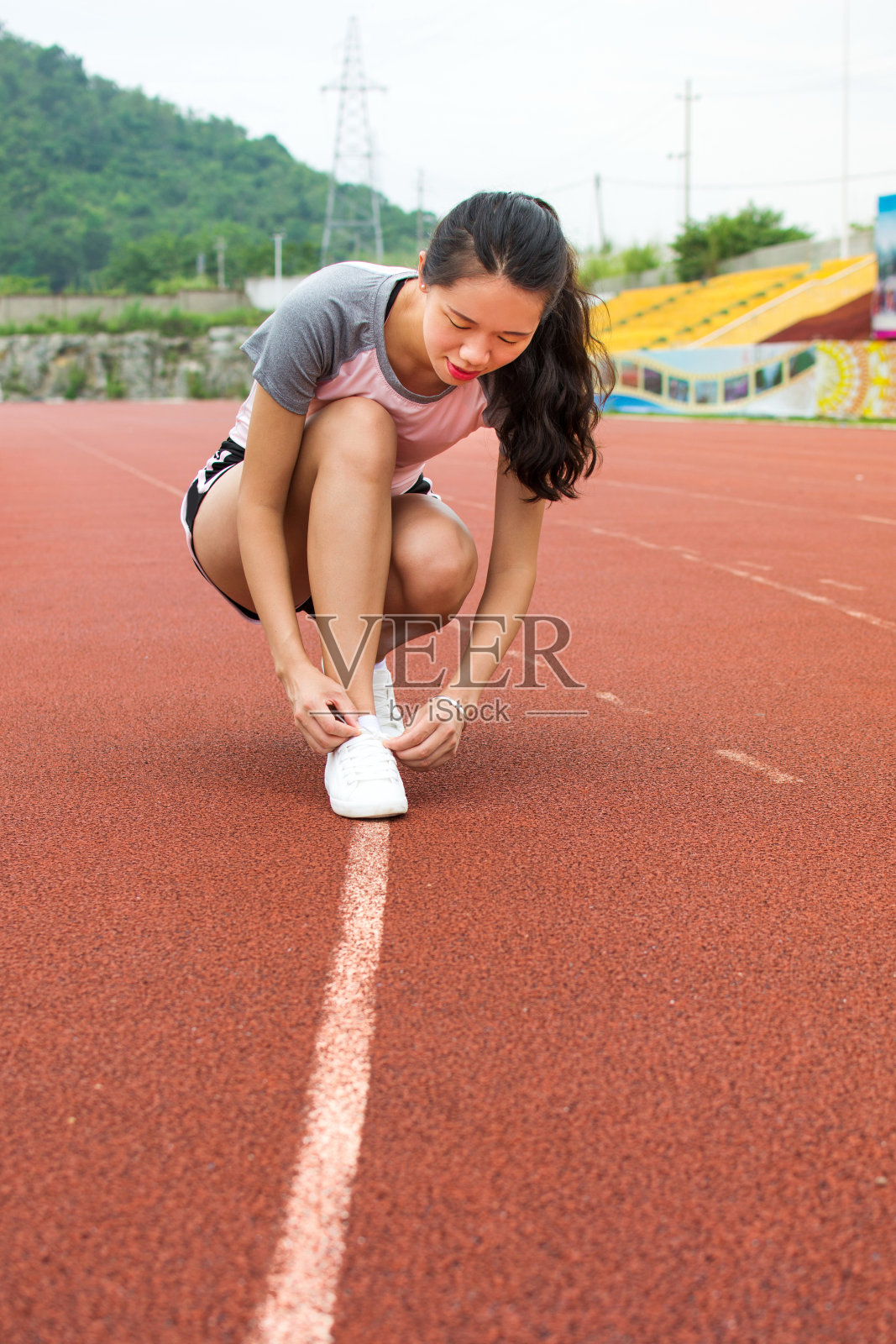 女孩在慢跑的跑道上系紧鞋带照片摄影图片