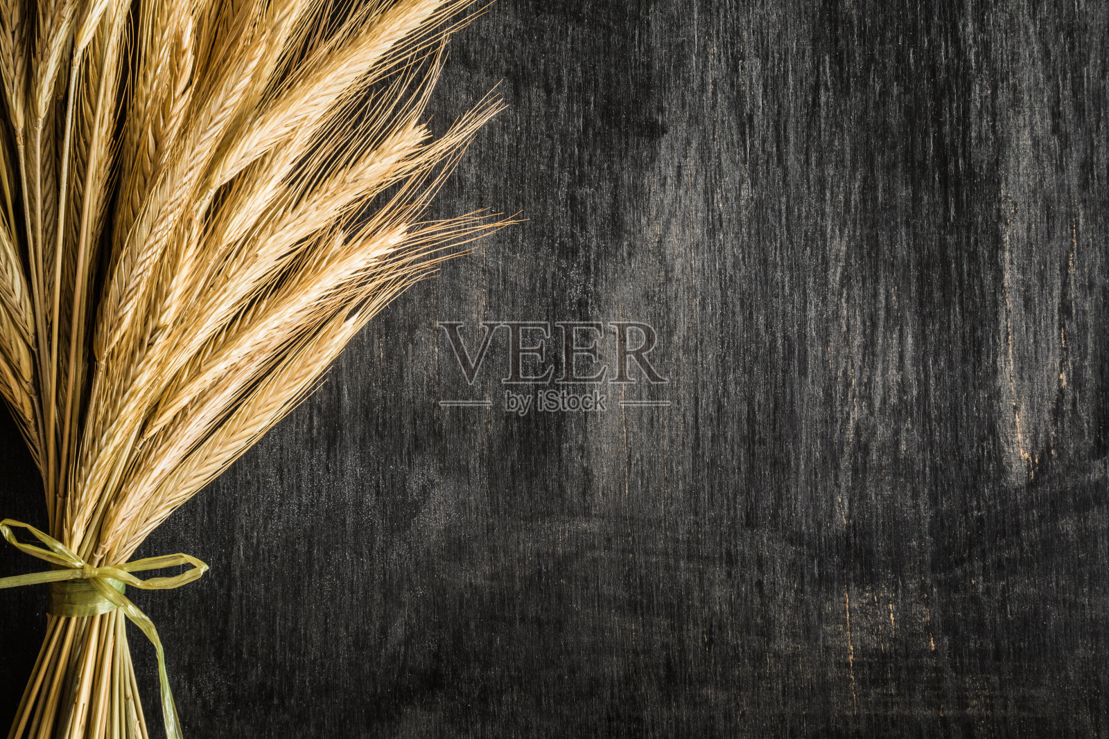 晒干的麦穗放在深色的木桌上。乡村的气氛。收获的背景。前视图。照片摄影图片