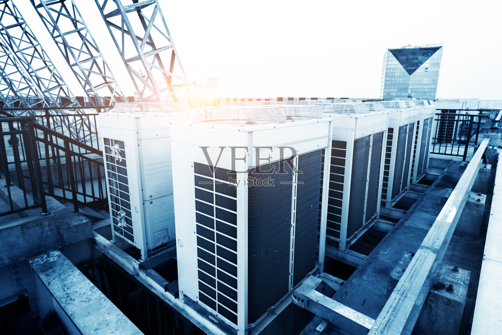 空调机组(HVAC)位于工业建筑的屋顶上，背景是蓝天和白云。照片摄影图片