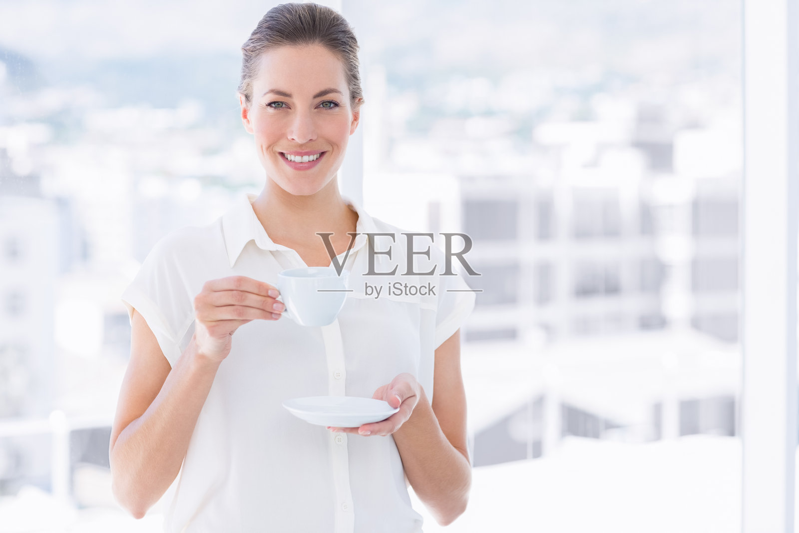 办公室里微笑着拿着茶杯的女商人照片摄影图片