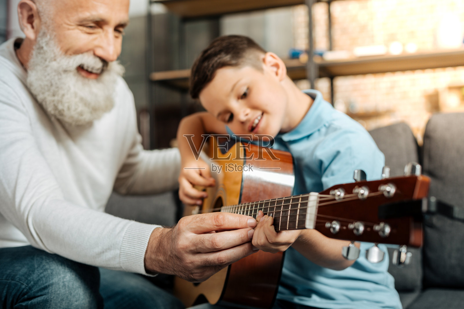 微笑的爷爷教孙子如何弹吉他照片摄影图片
