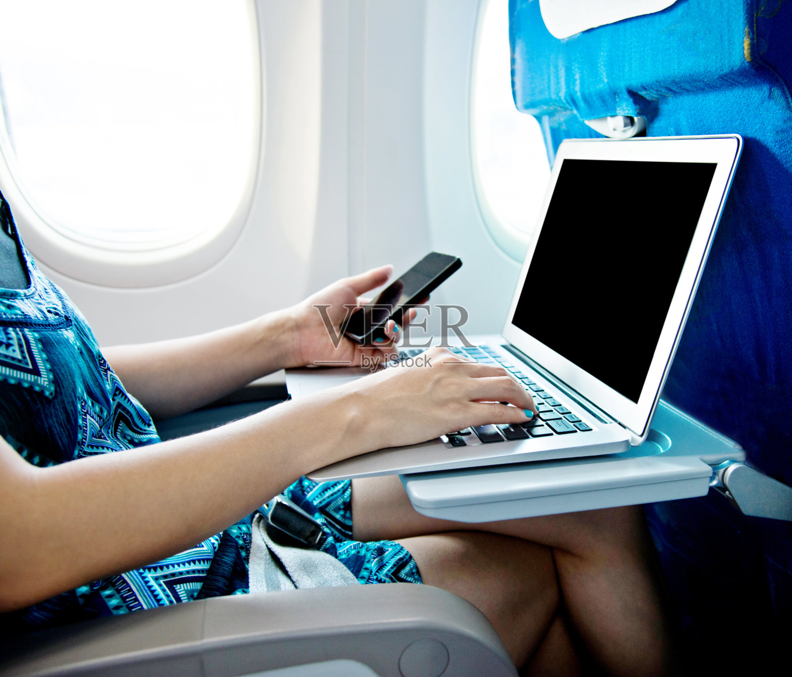 女性在飞机上使用智能手机和笔记本电脑照片摄影图片