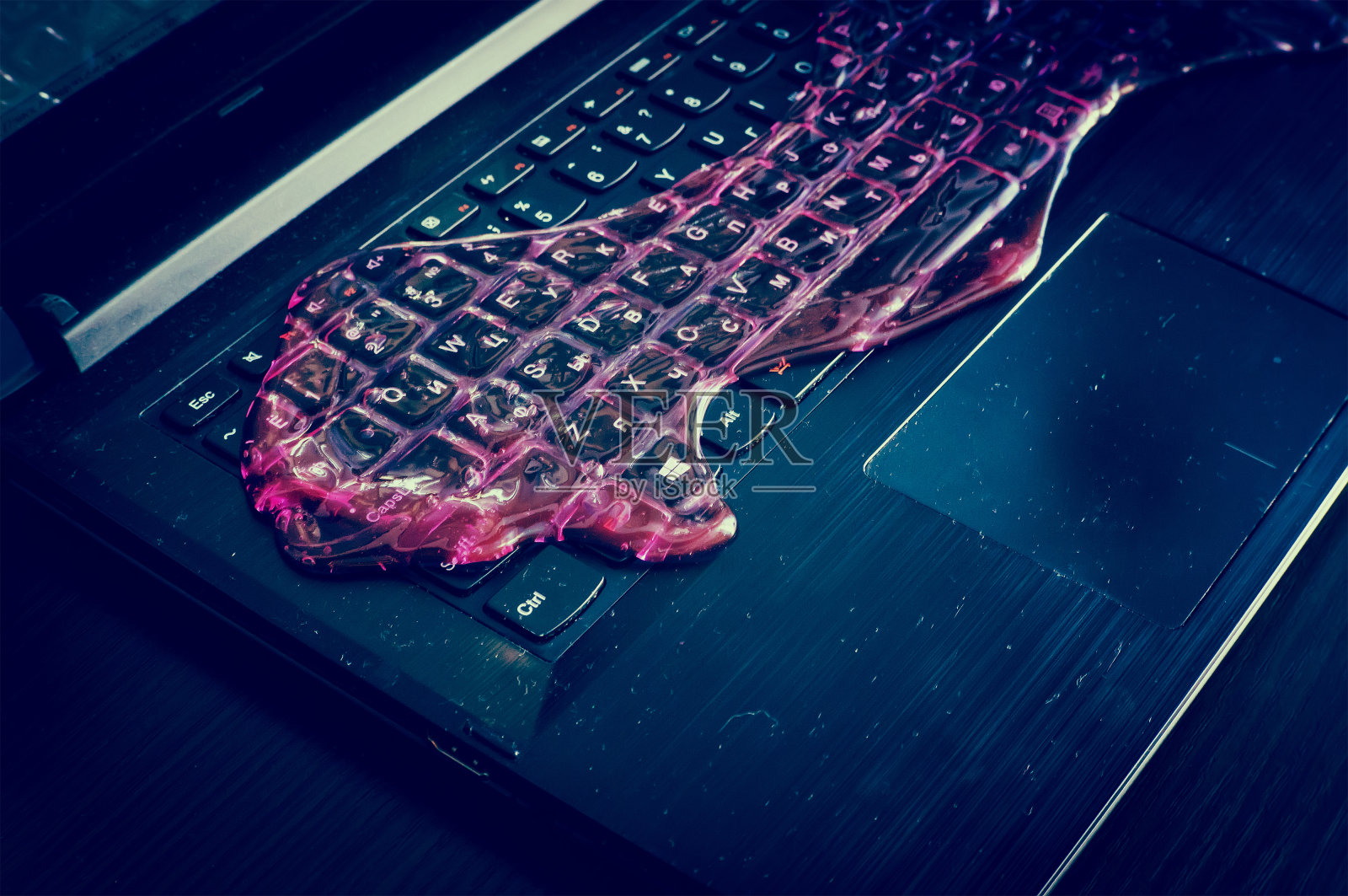 电脑键盘上布满了红色的黏液。照片摄影图片