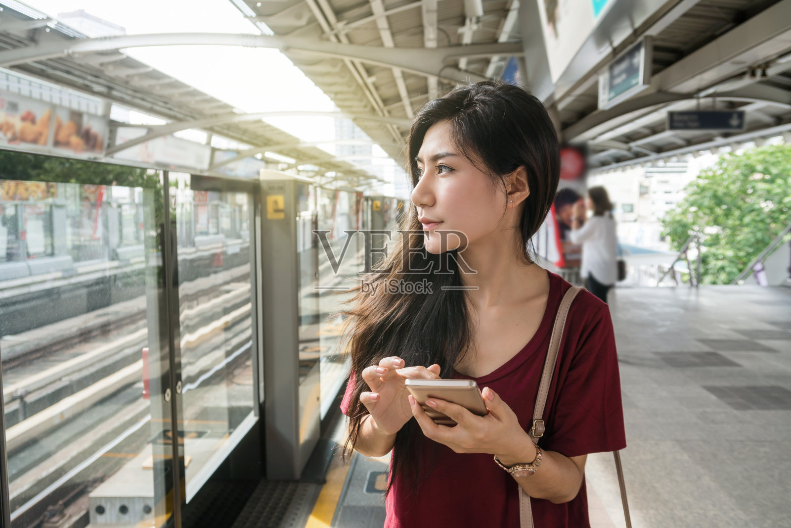 亚洲女性乘客休闲套装使用智能手机在BTS轻轨或捷运地铁在大城市旅行，生活方式和交通理念照片摄影图片