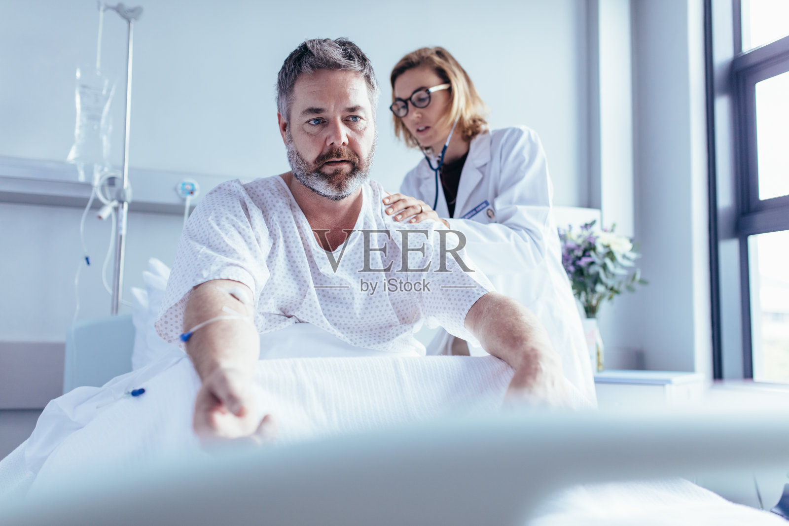医生在病床上给成熟的男子检查身体照片摄影图片