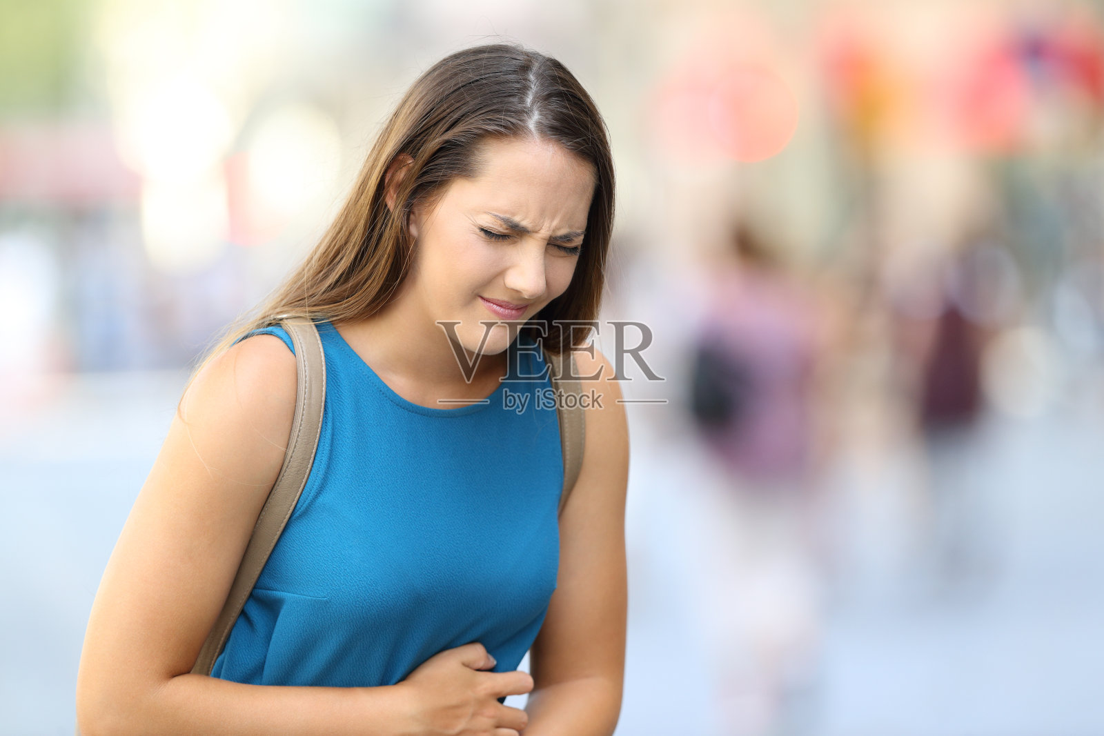 在街上忍受肚子疼痛的女人照片摄影图片