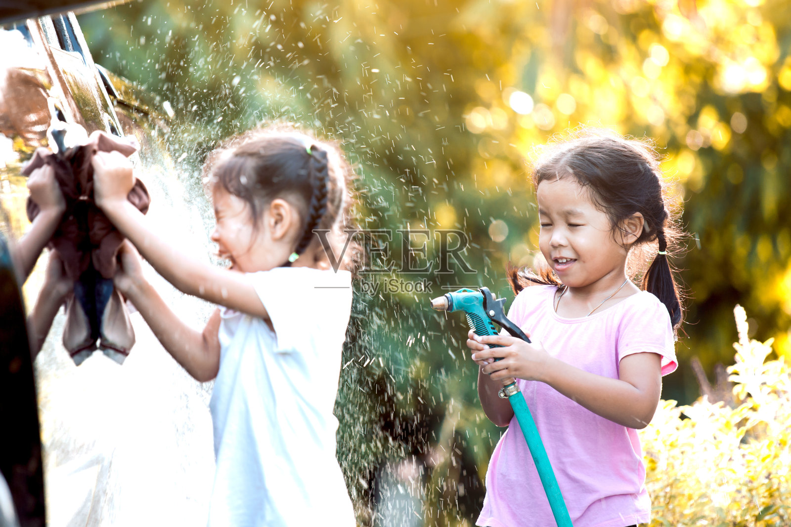两个快乐的亚洲女童有乐趣，以帮助父母洗车一起与阳光照片摄影图片