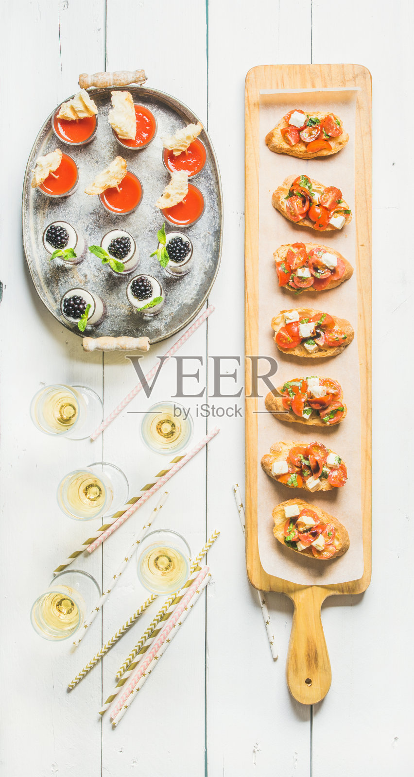 Brushettas，西班牙凉菜汤，甜点，香槟和吸管在白色的背景照片摄影图片