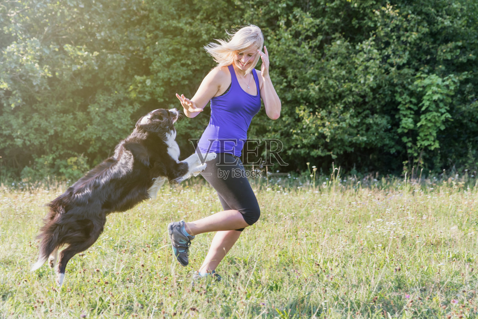 年轻的金发女人带着她的狗在跑步照片摄影图片