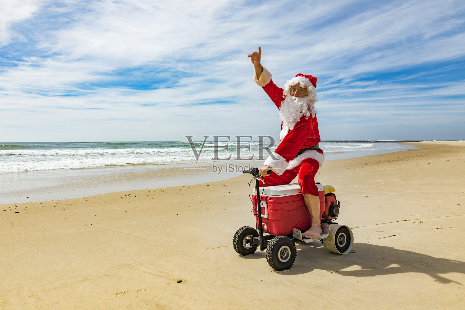 海滩上的圣诞老人骑着电动埃斯基冷却器照片摄影图片