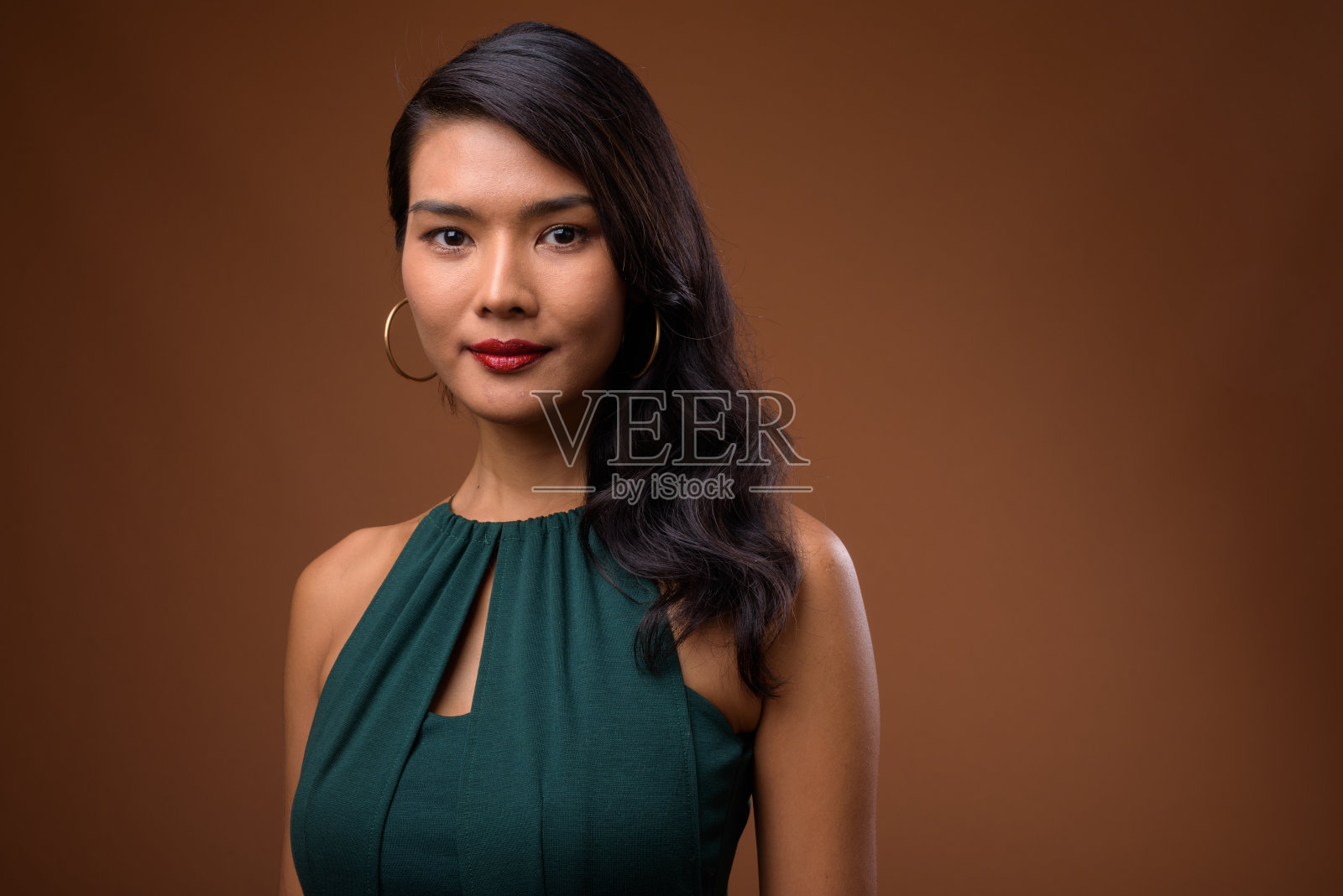 工作室拍摄的美丽的亚洲女商人穿着正式的绿色连衣裙，以彩色的背景照片摄影图片