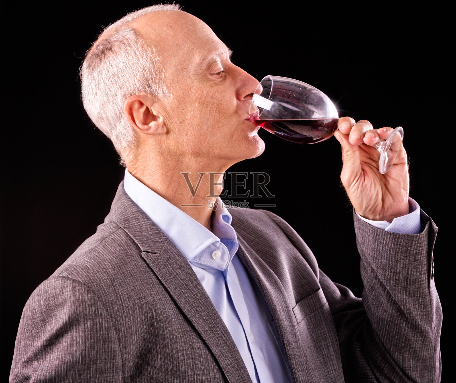 成熟的商人品尝着一杯红酒，闭着眼睛照片摄影图片