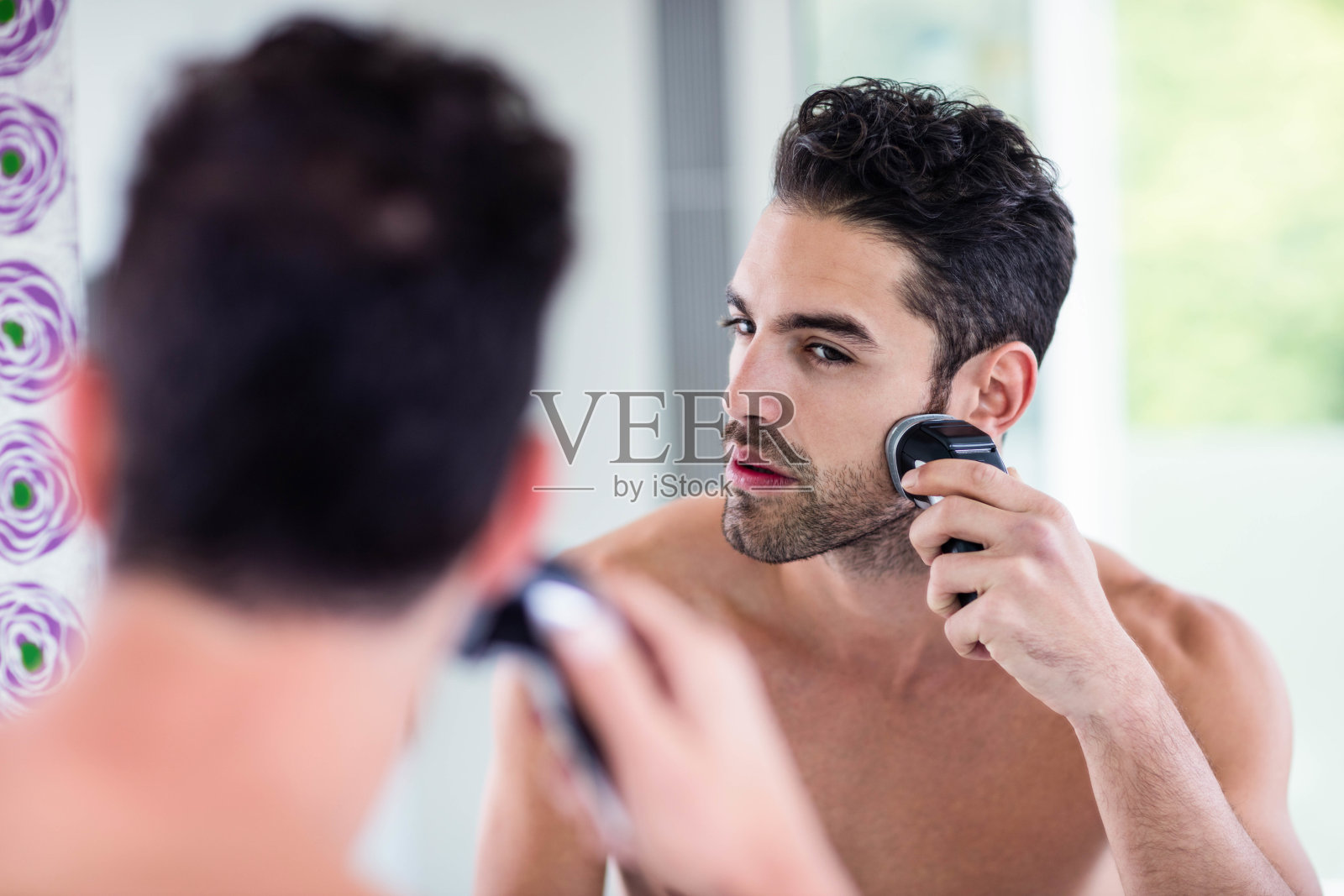 英俊的男人在镜子里刮胡子照片摄影图片