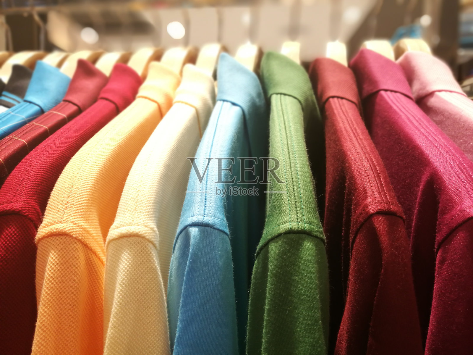 不同颜色的男式衬衫挂在零售服装店的衣架上照片摄影图片