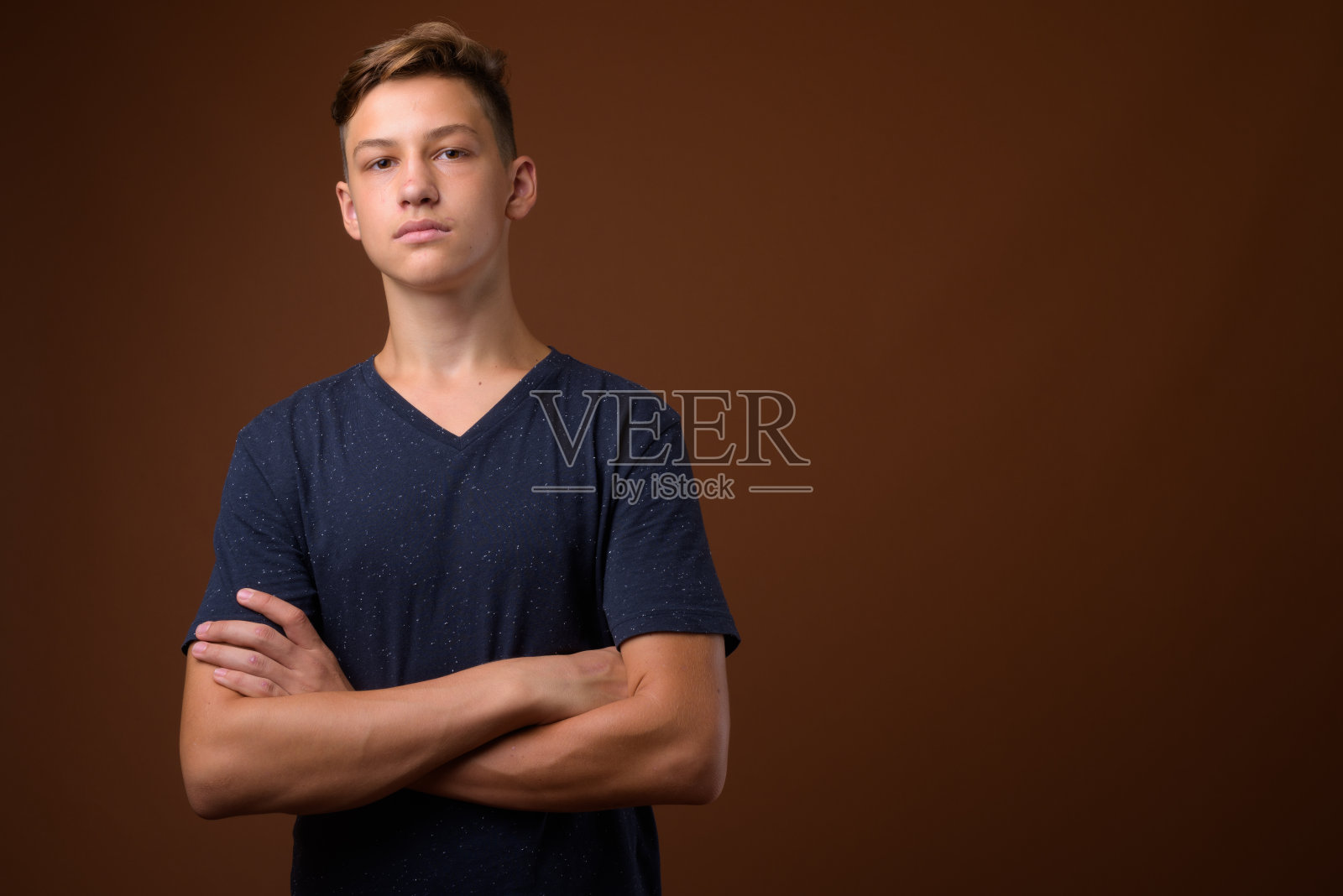 工作室拍摄的年轻英俊的十几岁的男孩穿着蓝色的衬衫，以彩色的背景照片摄影图片
