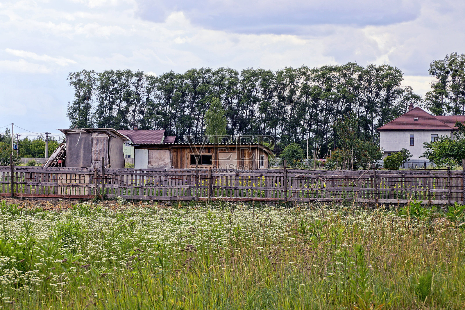 田野里篱笆后面的旧木头建筑照片摄影图片
