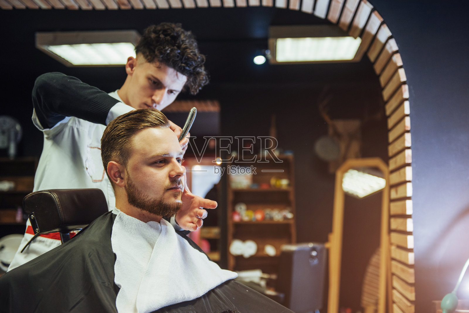 男士理发师在男士发廊里为成年男士理发照片摄影图片