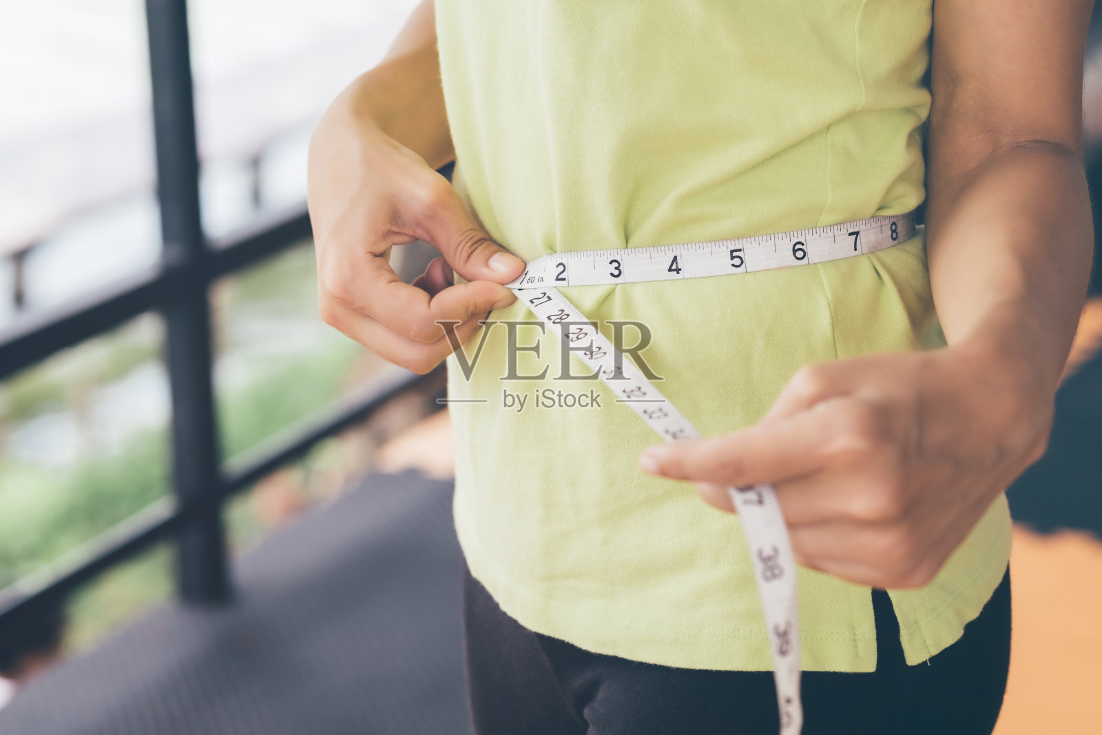 十几岁的女孩使用自己的腰围测量带。锻炼后控制自己的体型。照片摄影图片