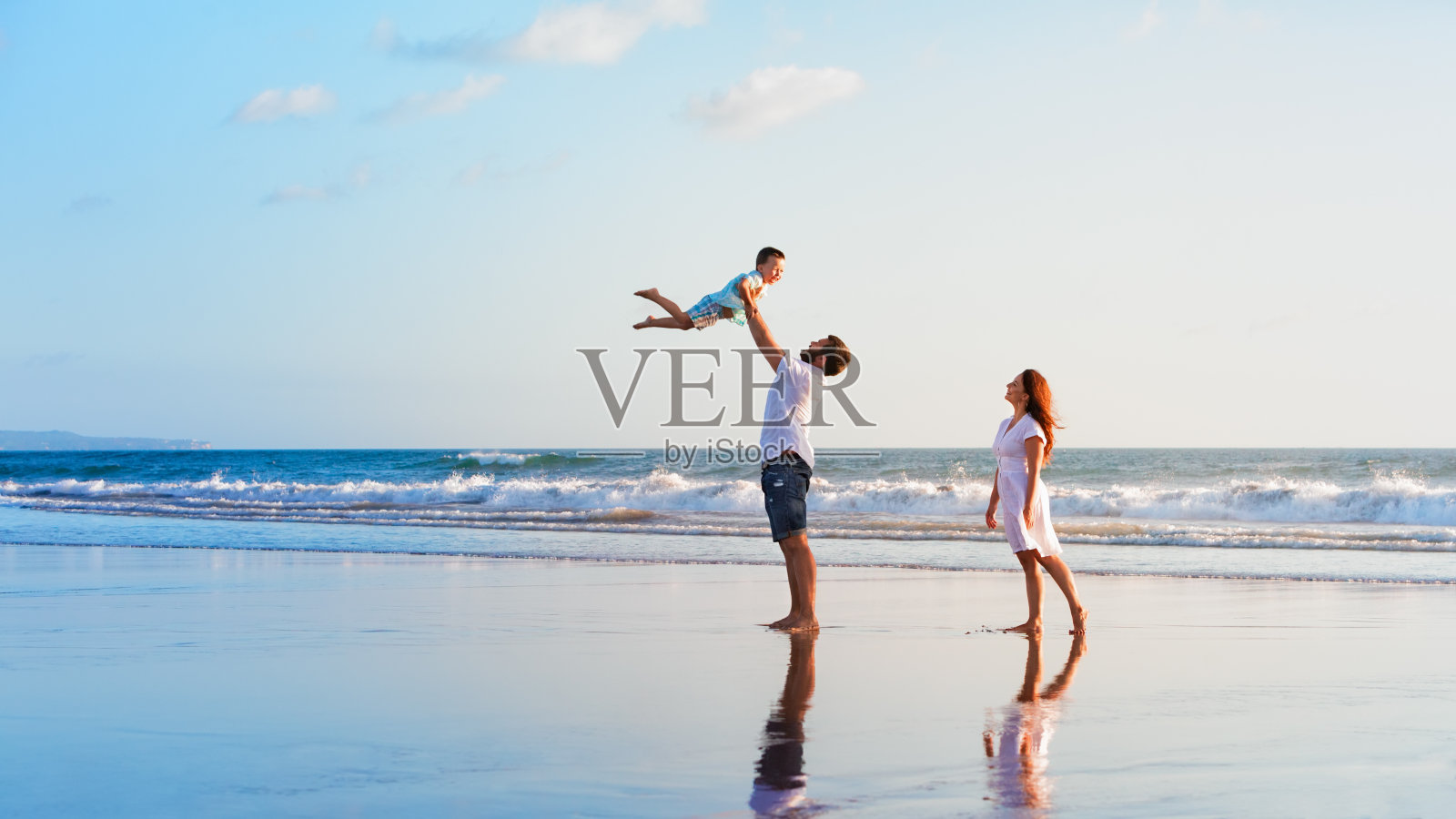家庭-父亲，母亲，婴儿散步在日落海滩照片摄影图片
