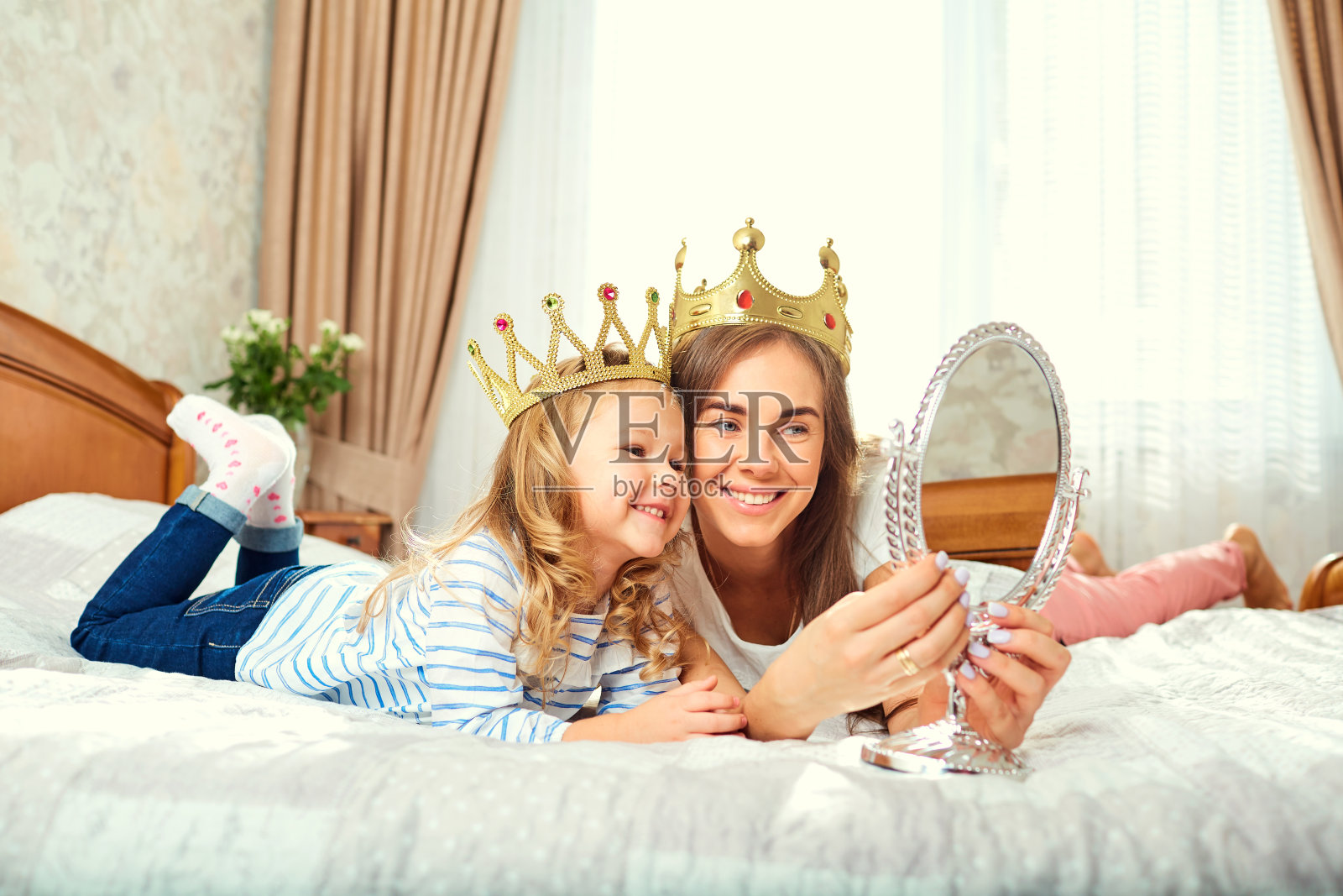 母亲和女儿戴着皇冠在屋顶上玩镜子照片摄影图片