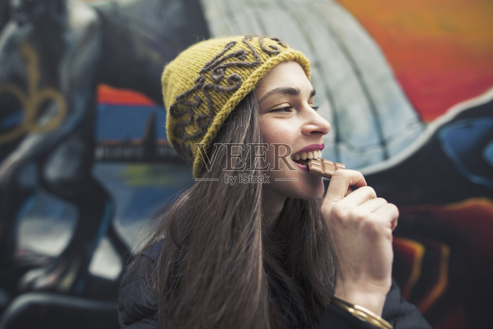 一个美丽的年轻女子咬着巧克力棒的偷拍照片照片摄影图片