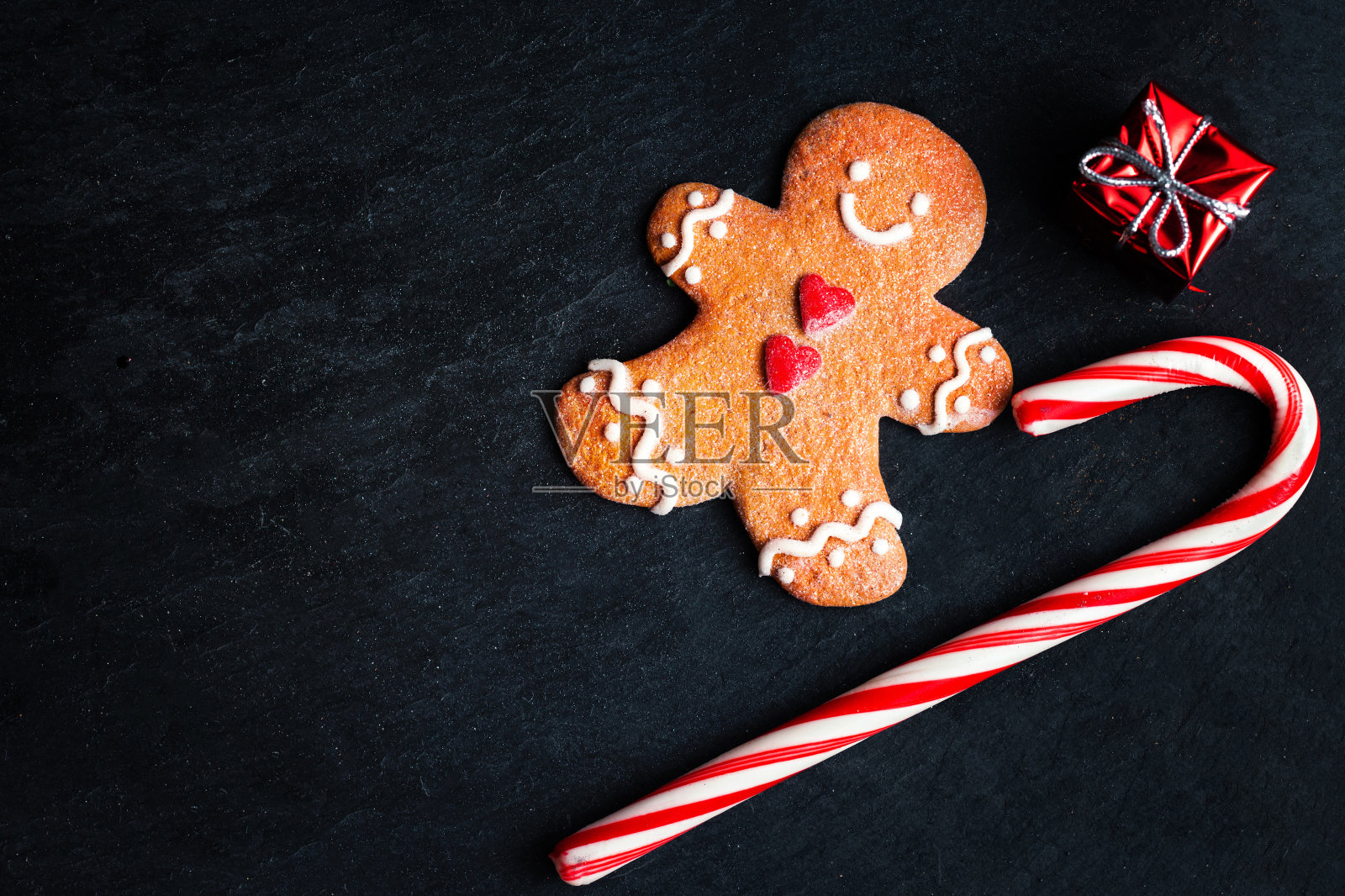 圣诞装饰圣诞礼盒，姜饼人饼干和糖果条纹红棒在黑暗的背景与copyspace。圣诞节日符号照片摄影图片
