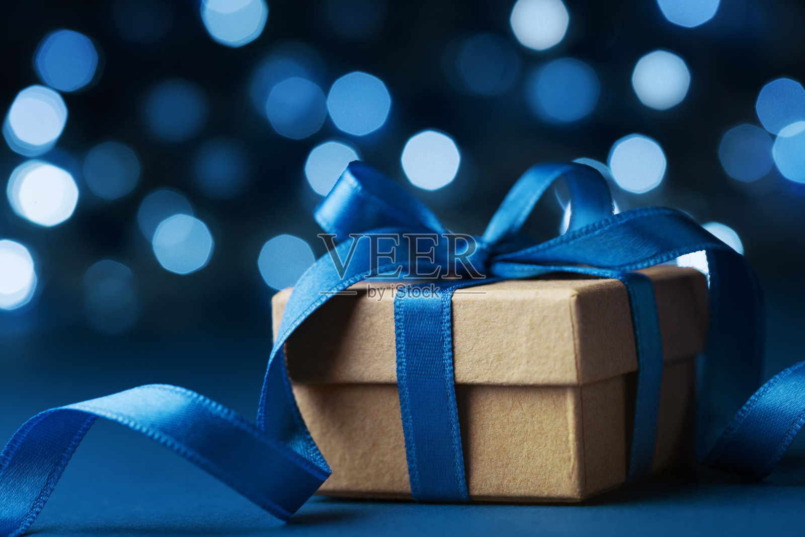 以蓝色散景为背景的圣诞礼盒或礼物。节日贺卡。照片摄影图片