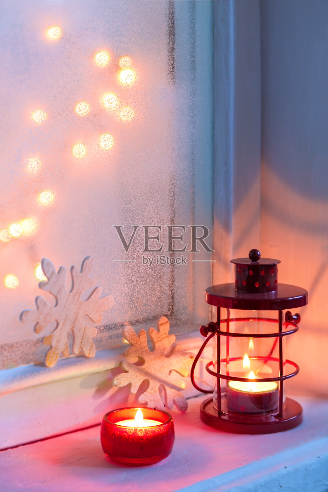 红色的圣诞灯笼和烛光在黄昏的旧窗台上。照片摄影图片