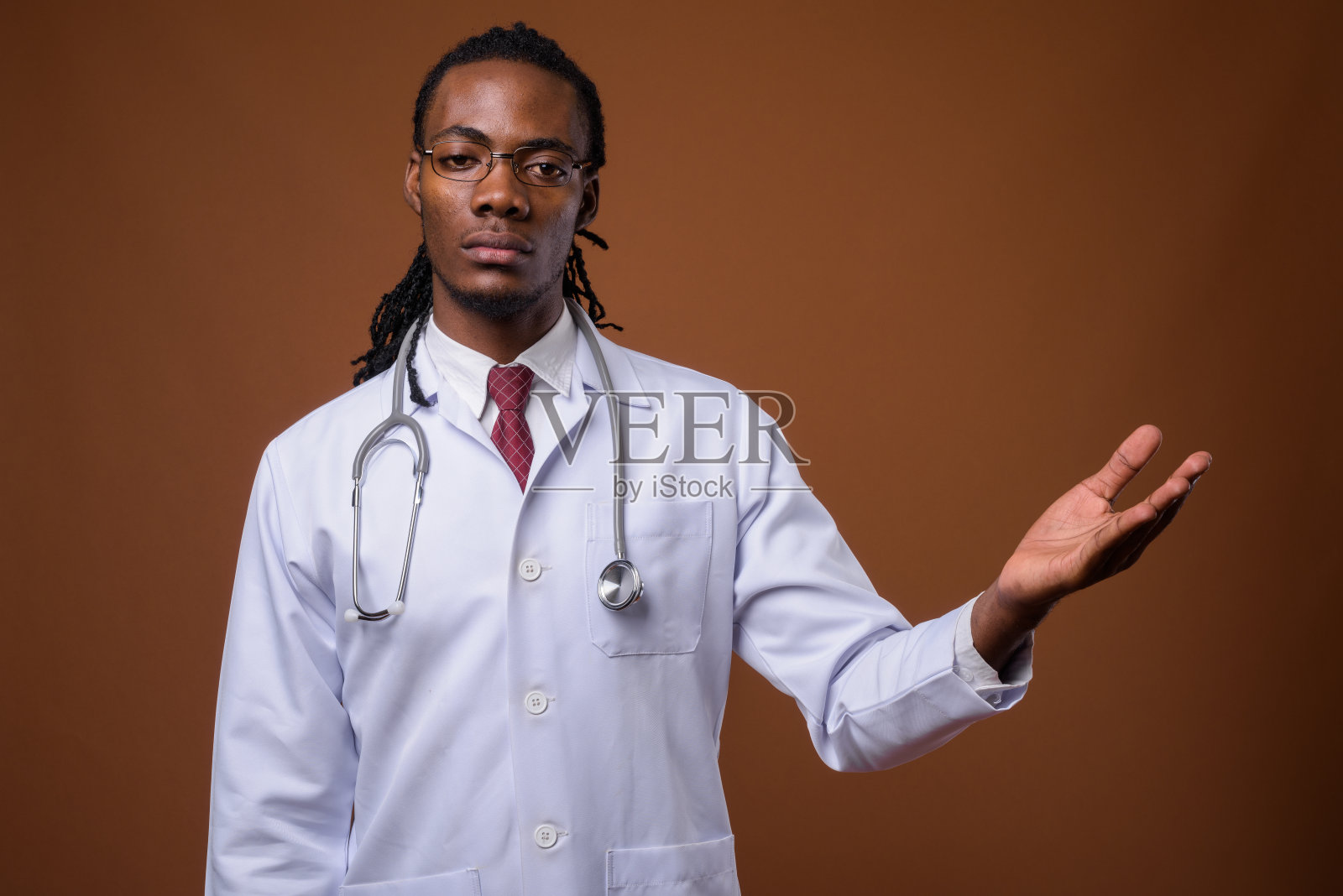 工作室拍摄的年轻英俊的非洲男子医生戴眼镜，以有色的背景照片摄影图片