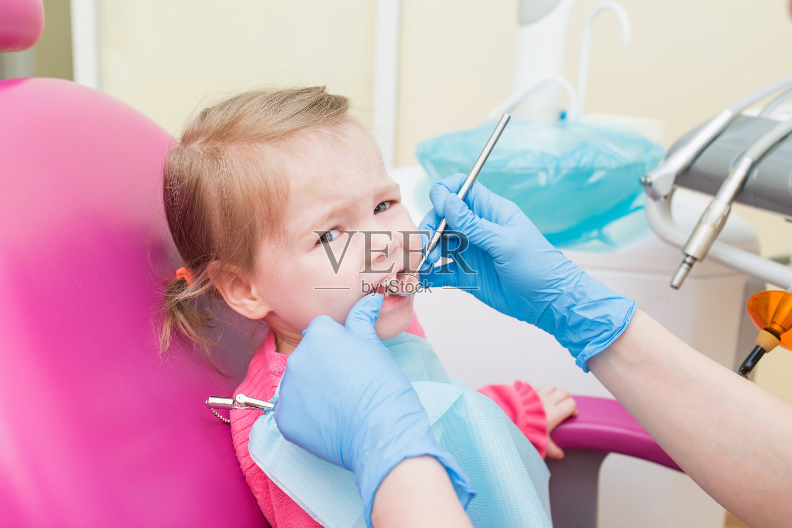 可爱的小女孩坐在牙医办公室的牙科椅子上，特写肖像照片摄影图片