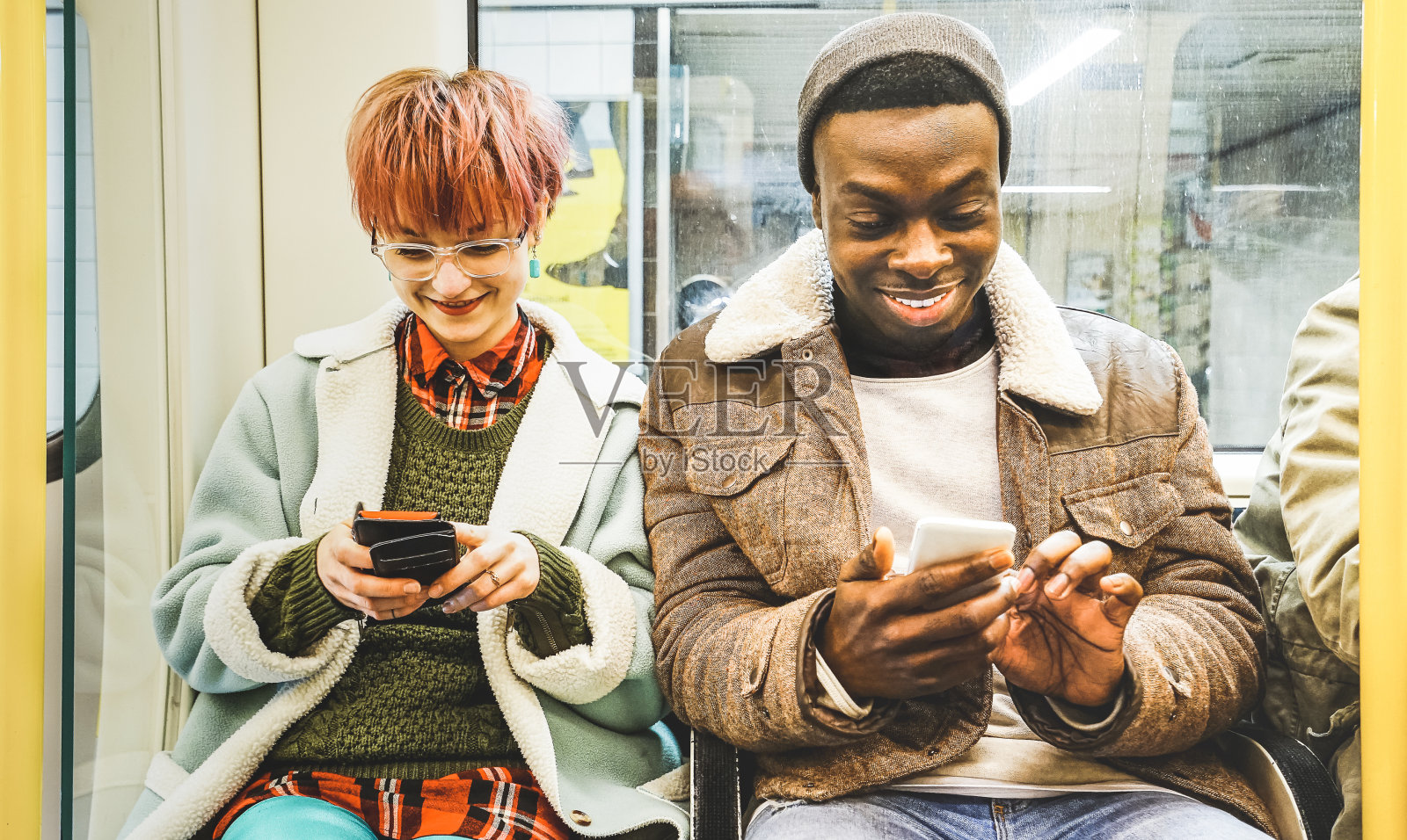 多种族的潮人朋友夫妇在地铁里玩智能手机-城市关系概念和年轻人在城市地下区域看手机-明亮的去饱和滤镜照片摄影图片