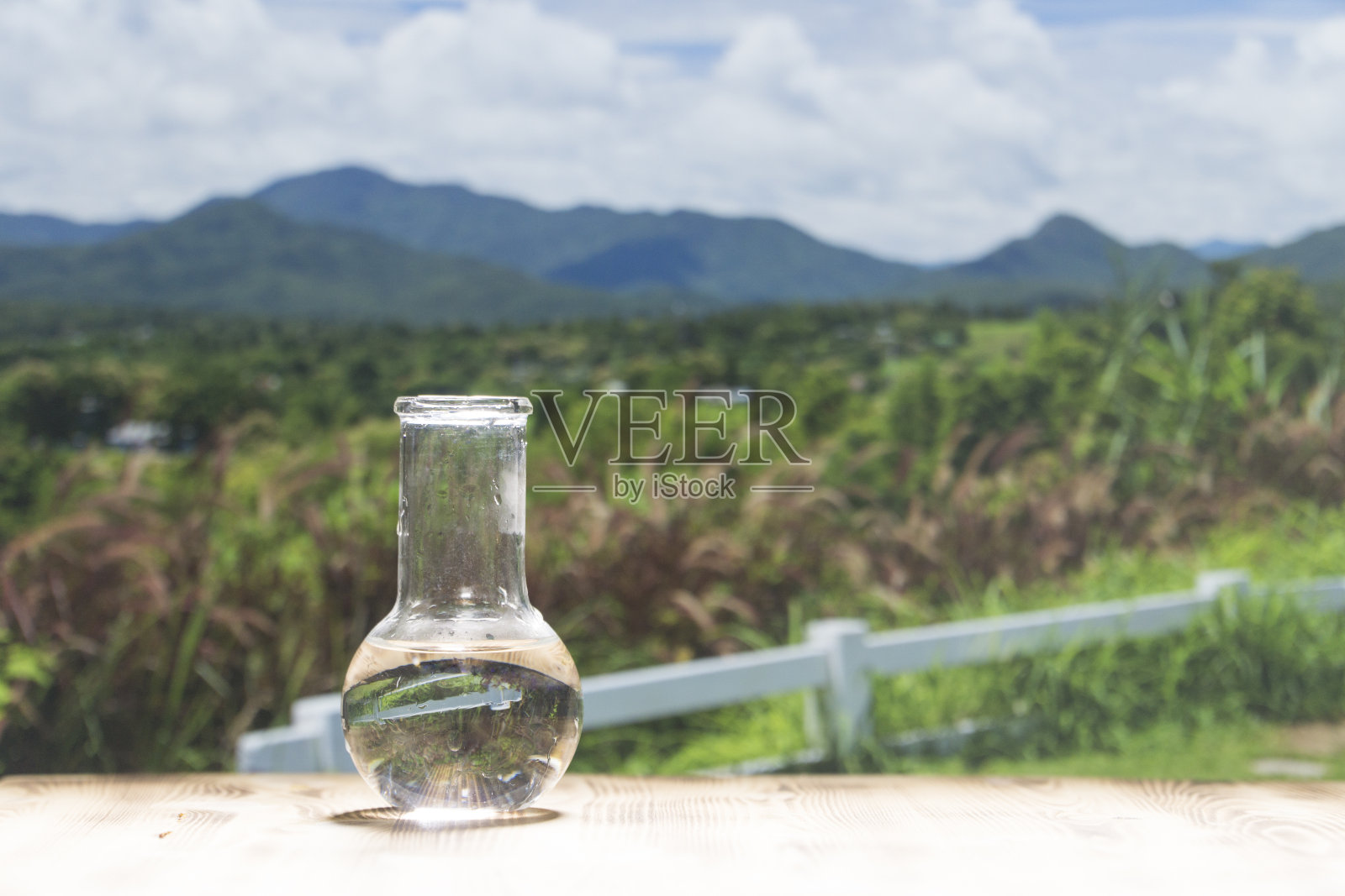 在山背景的木桌上的实验室玻璃烧瓶里装着干净的水。32、生态理念，保护水资源，检验水的纯度和质量照片摄影图片