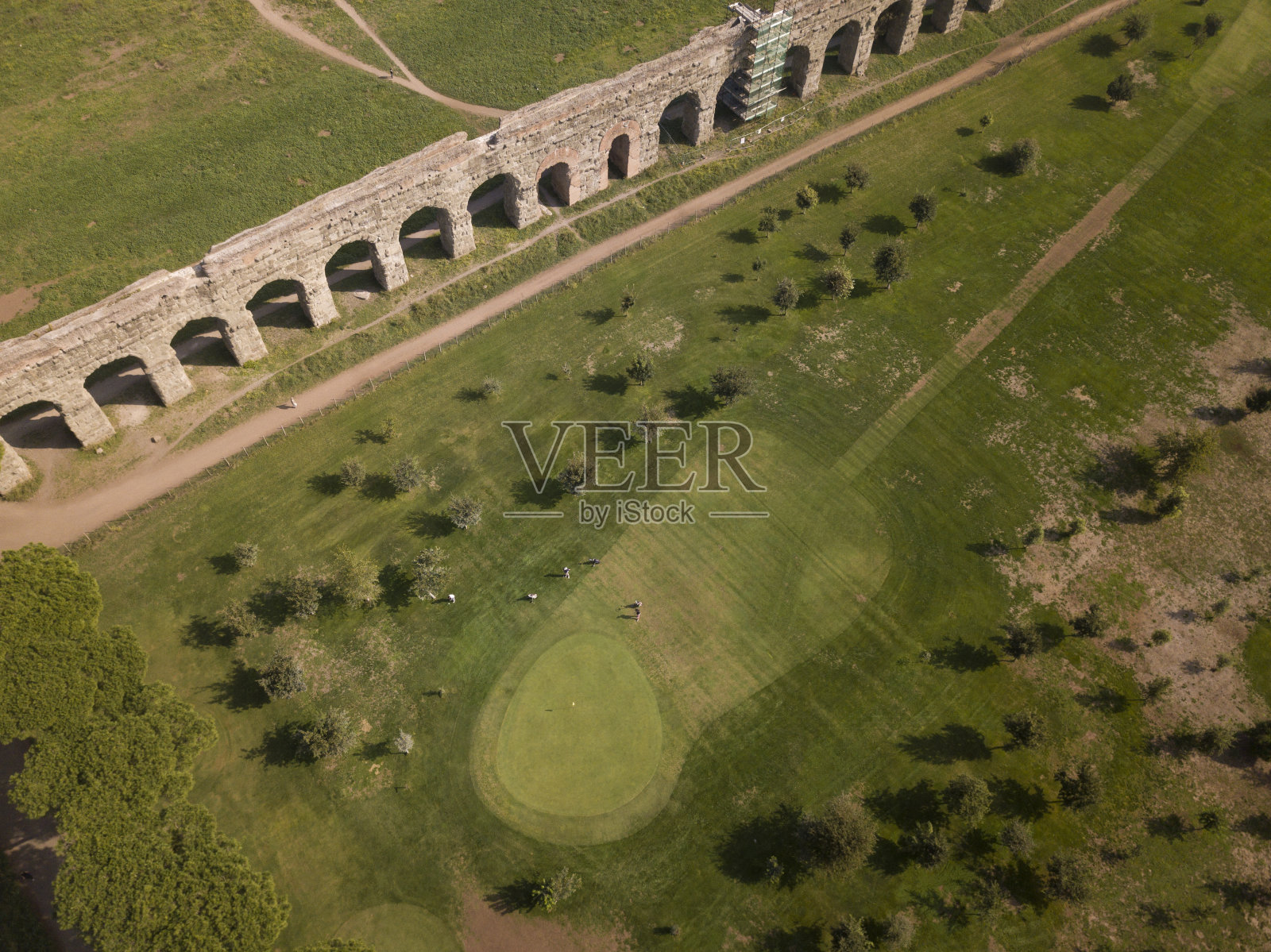 意大利罗马，一些人在古罗马渡槽附近的球场上打高尔夫的鸟瞰图。照片摄影图片