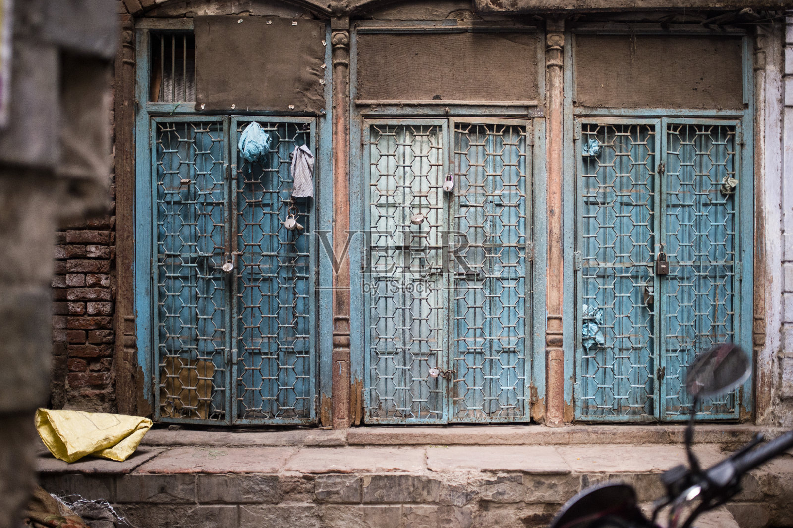 三扇带铁门和挂锁的蓝色上锁的门，印度新德里。照片摄影图片