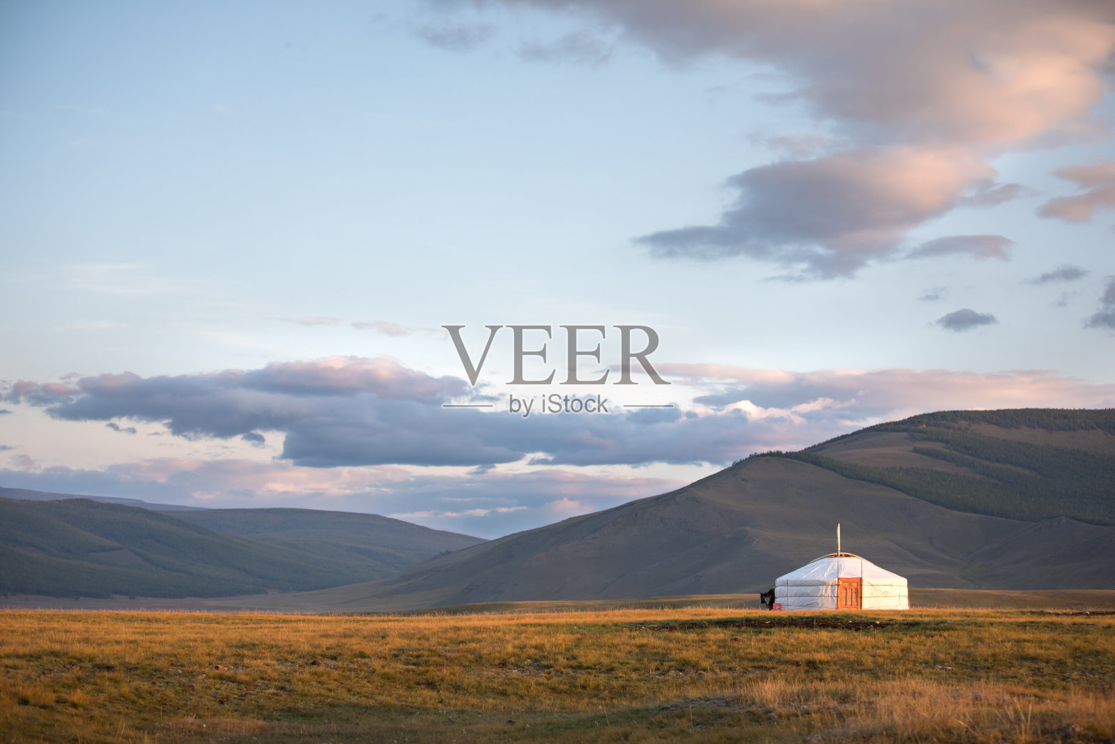 传统蒙古蒙古包在山的背景下日落的光。照片摄影图片