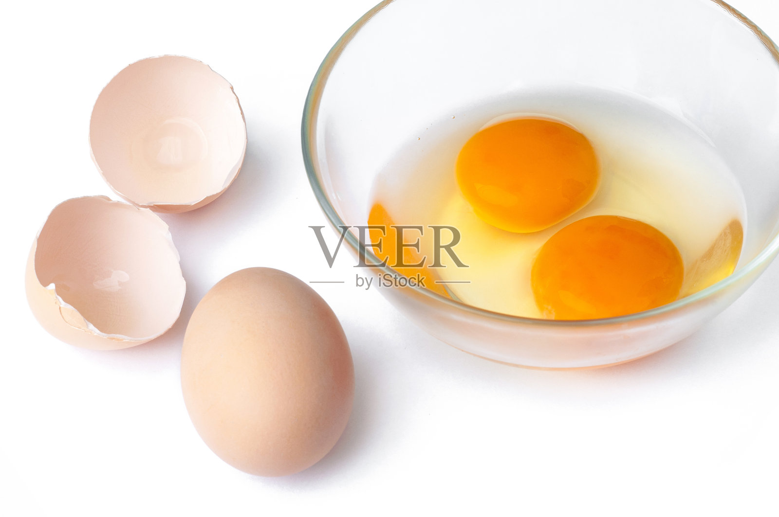 鸡蛋，鸡蛋和正在打鸡蛋的玻璃碗，棕色的蛋壳和白色的背景照片摄影图片
