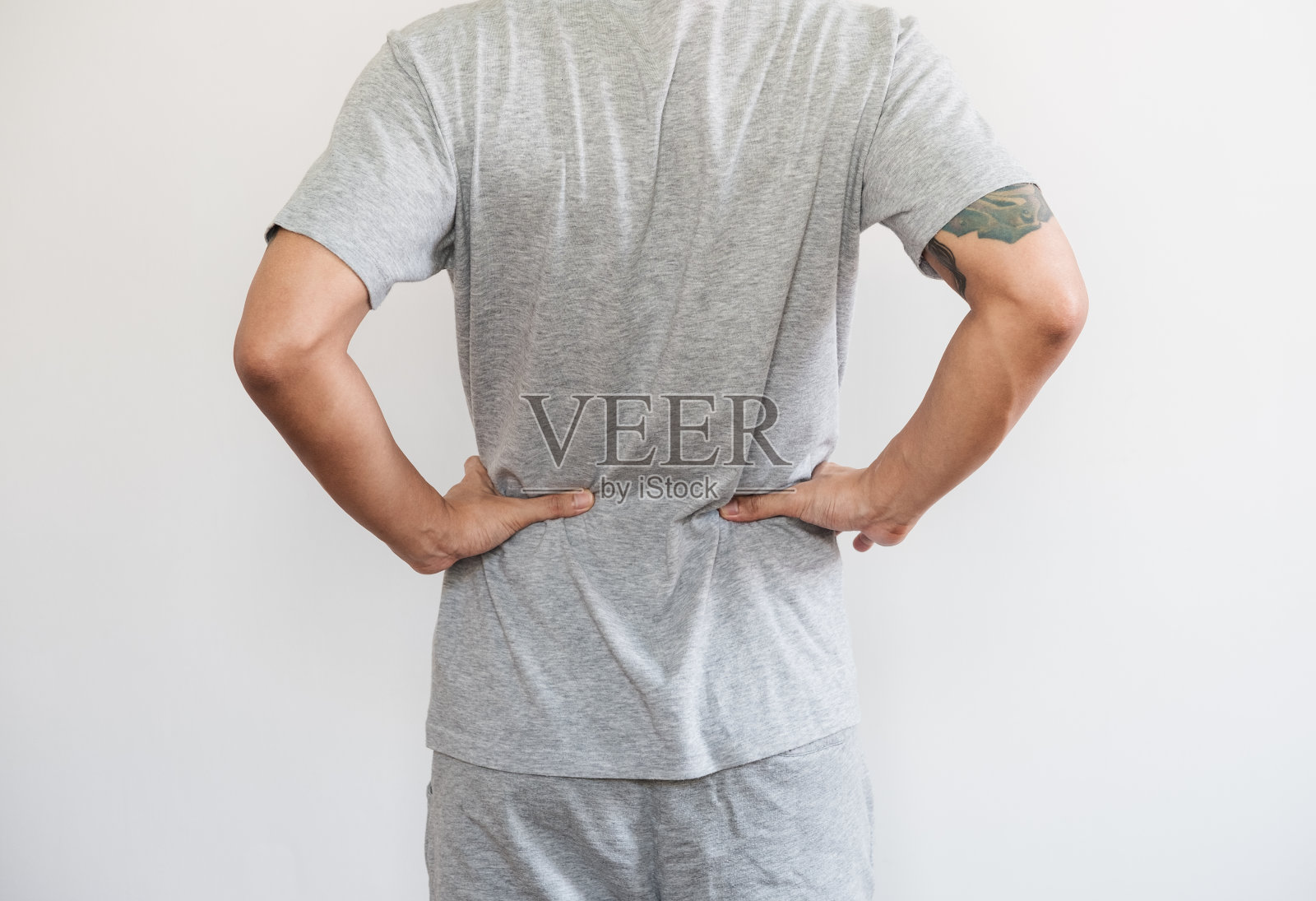 一个男人摸着他的背，背疼腰疼的概念，在白色的背景上照片摄影图片