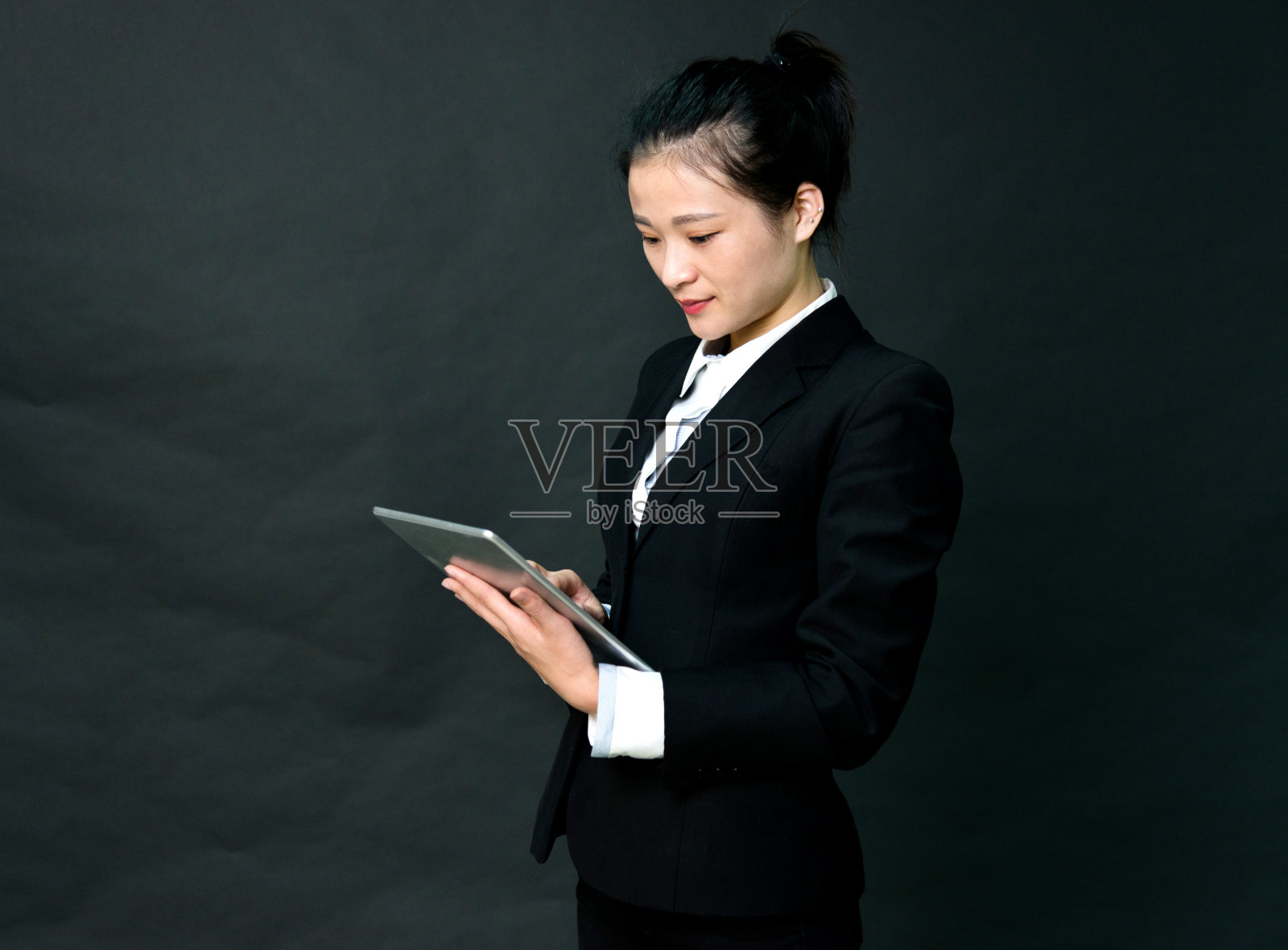 在黑色背景上拿着平板电脑的女商人照片摄影图片