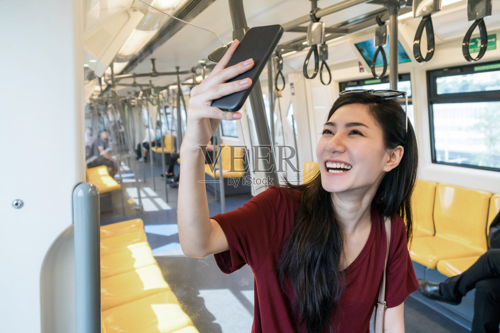 亚洲女性乘客穿着休闲服装，在轻轨或地铁上用智能手机自拍，以在大城市旅行，生活方式和交通理念照片摄影图片