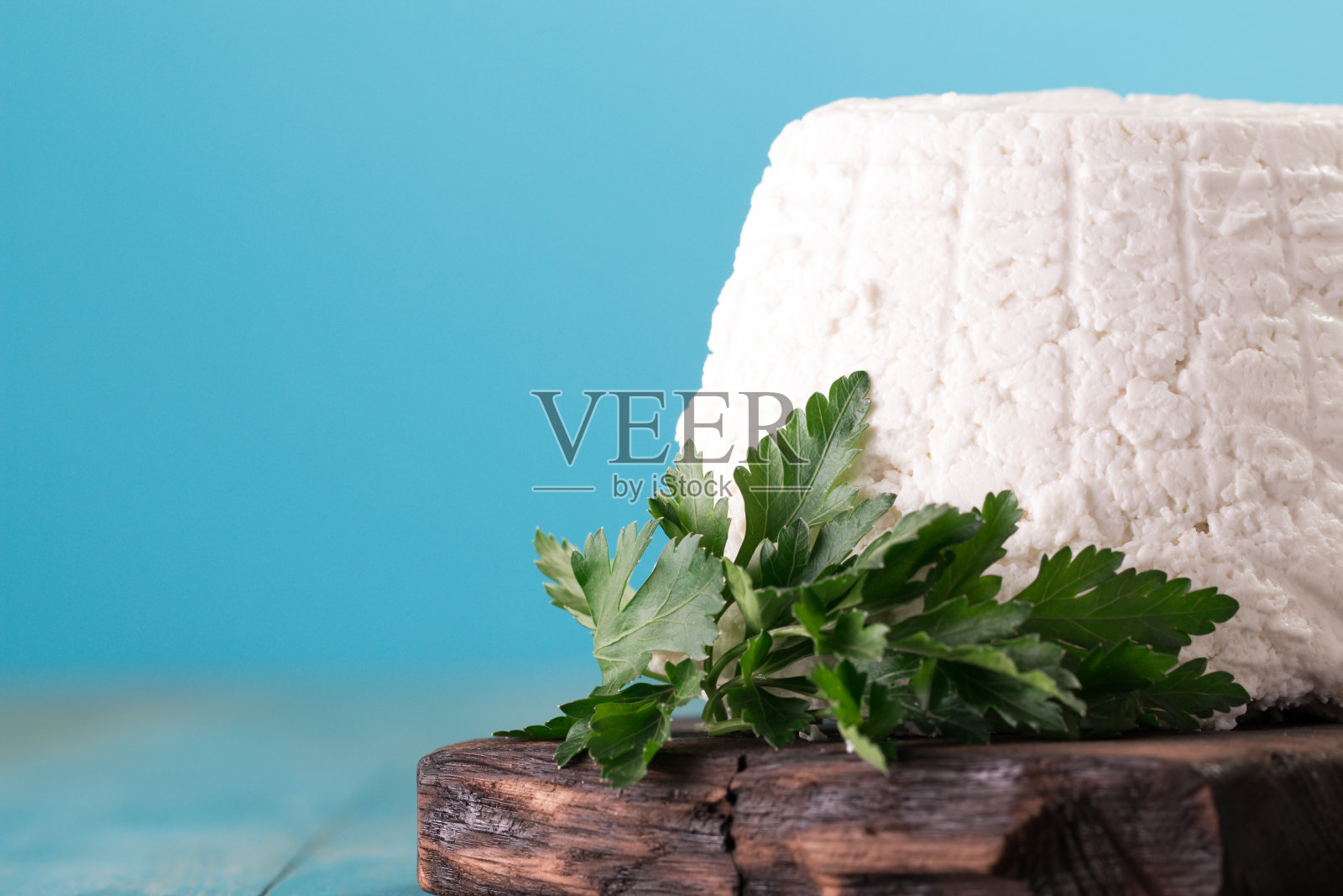 新鲜的乳清干酪和欧芹叶放在木桌上，意大利食物照片摄影图片