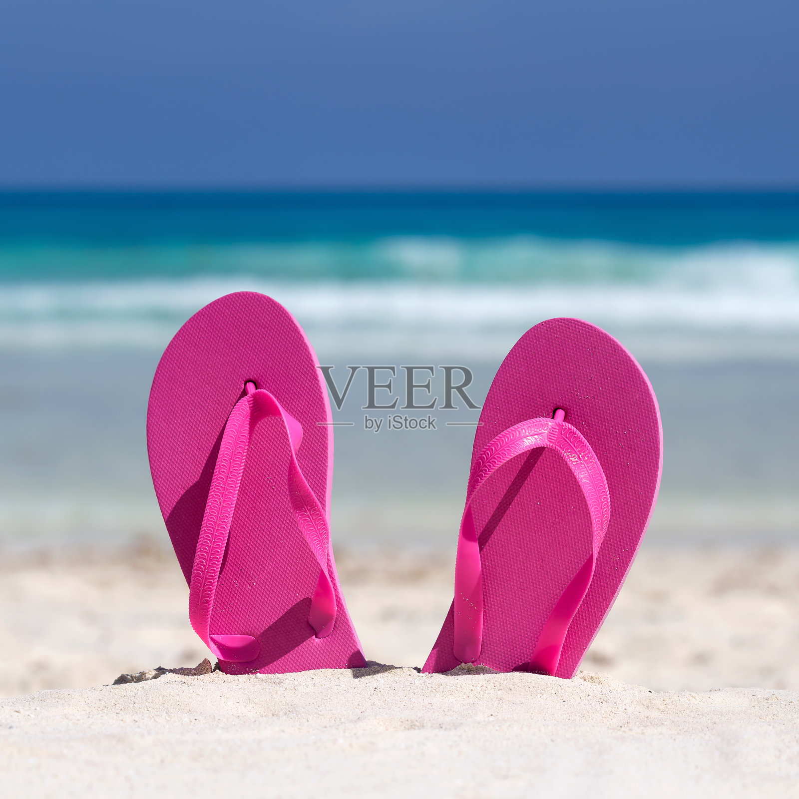 粉红色人字拖在海边的沙滩上。暑假的概念照片摄影图片