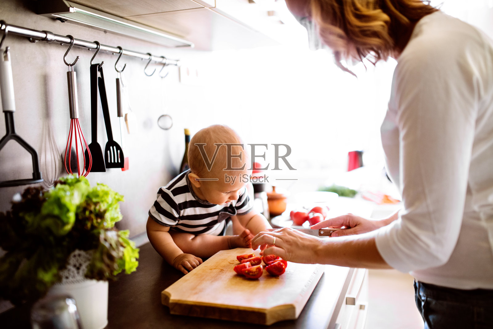 年轻的母亲带着一个小男孩做家务。照片摄影图片