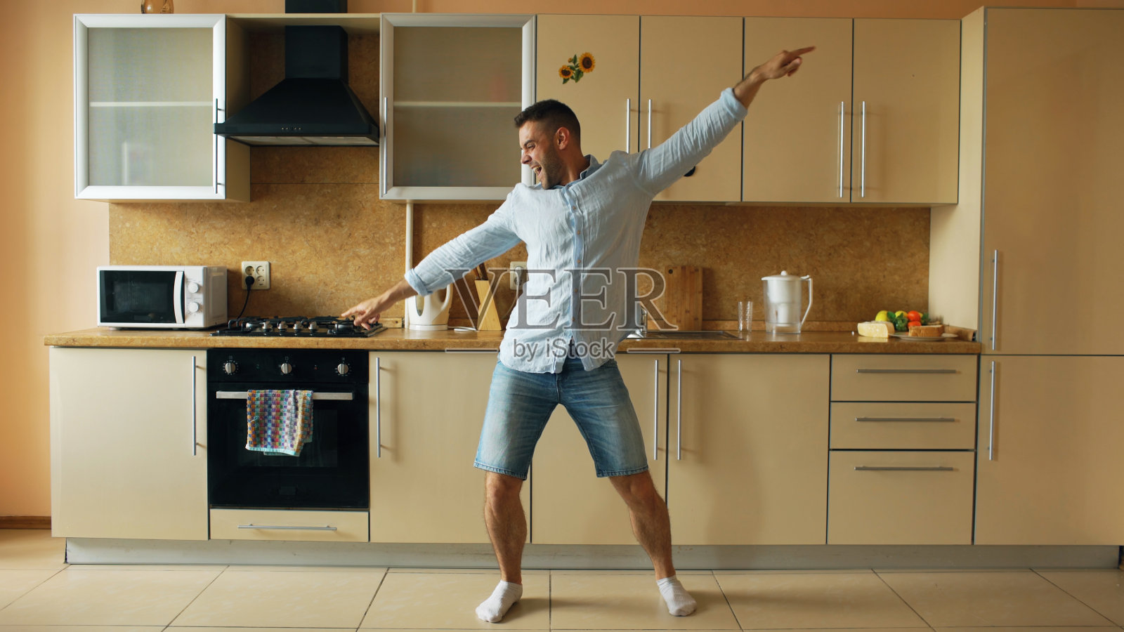 英俊的年轻有趣的男人在厨房跳舞在家里的早上和有乐趣的假期照片摄影图片