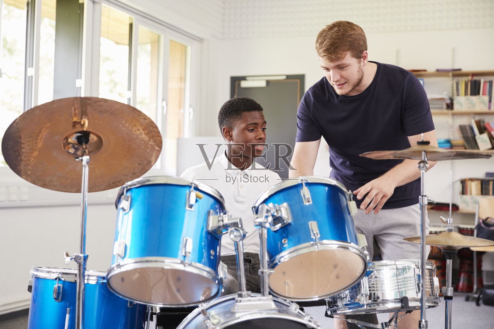 音乐课上，男生和老师一起打鼓照片摄影图片