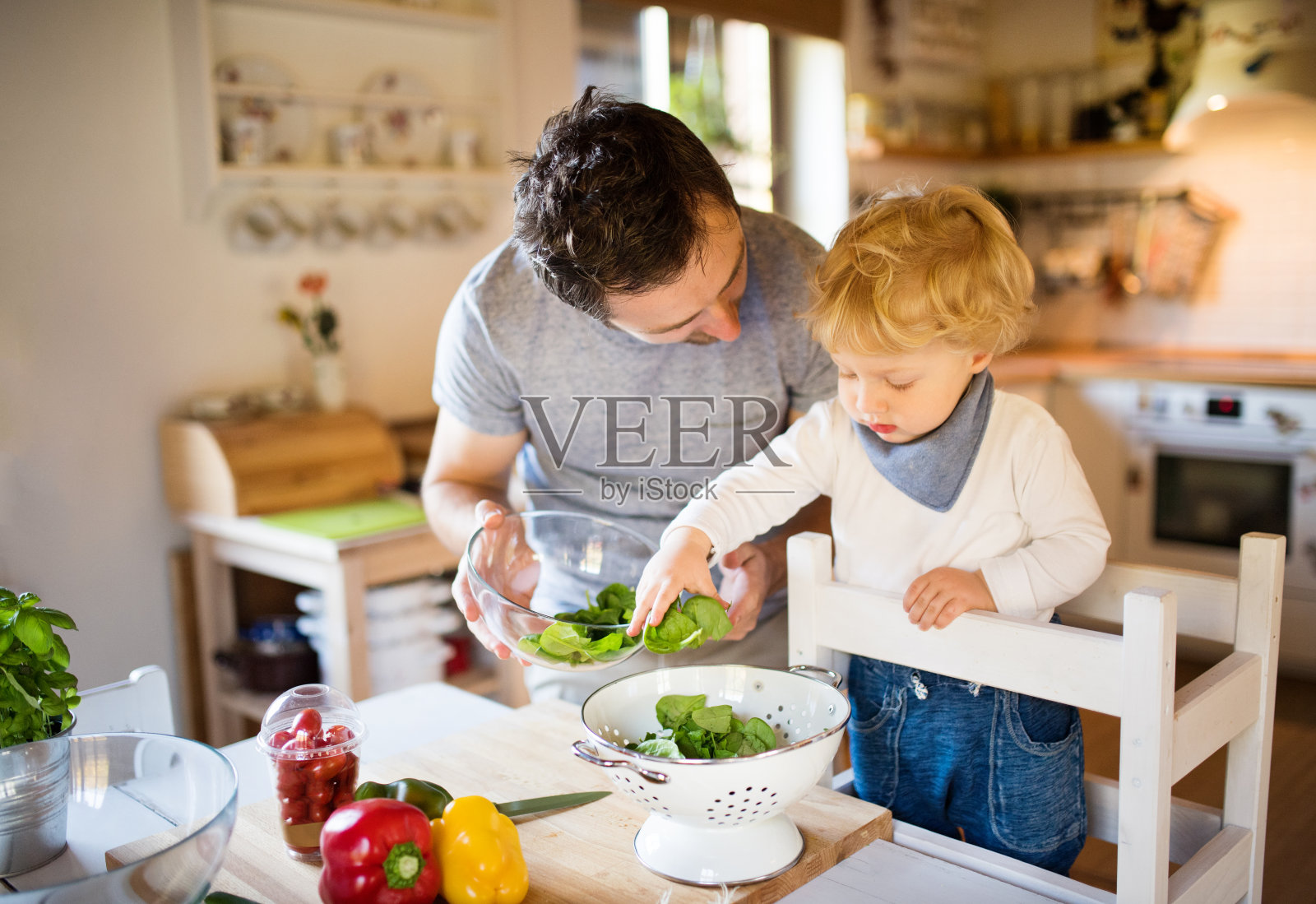 年轻的父亲和一个蹒跚学步的男孩做饭。照片摄影图片