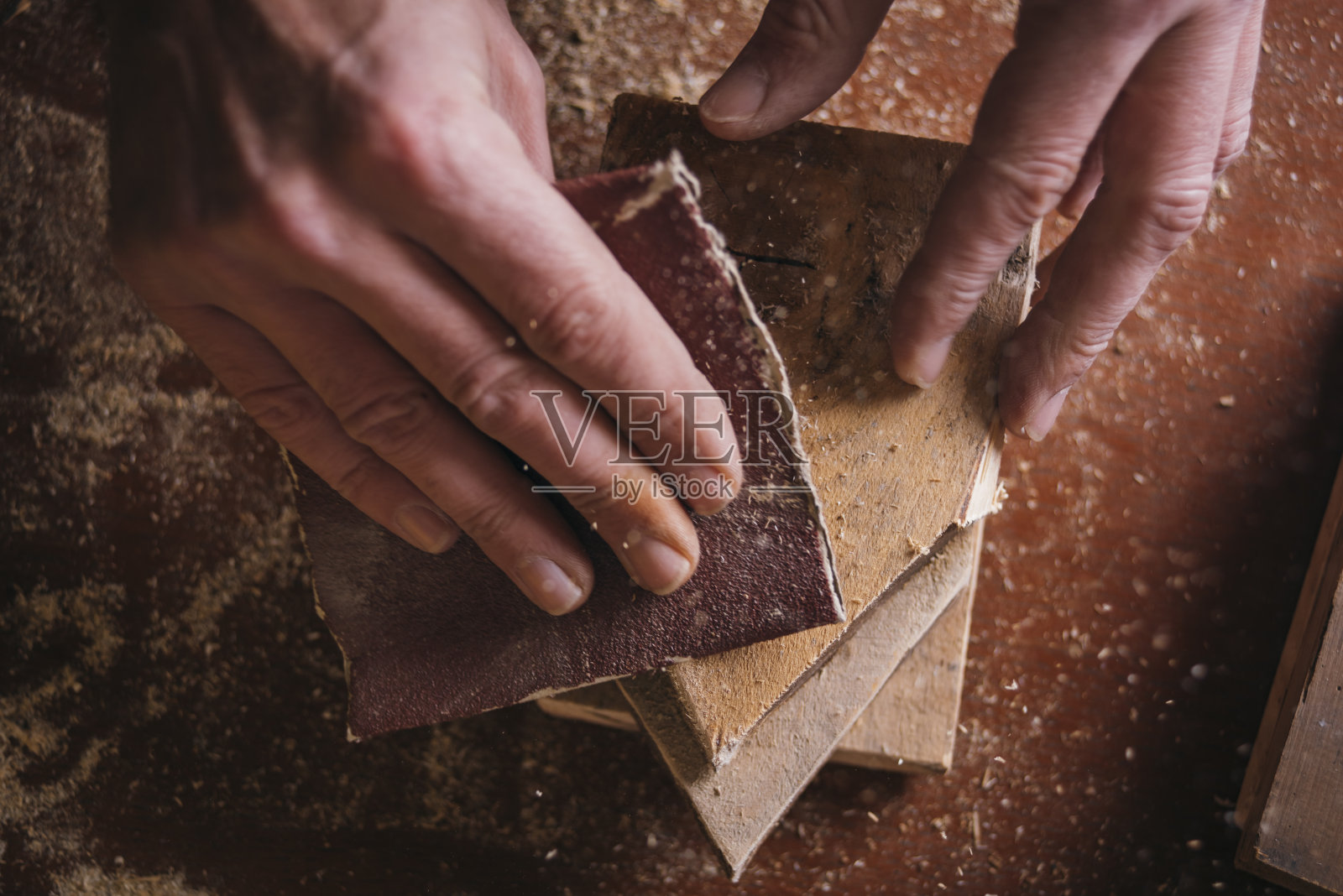 业余木匠把砂纸涂在木头上照片摄影图片